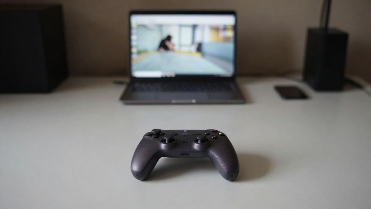 Imagen ilustrativa: un mando de videojuegos sin marcas sobre una mesa en una habitación con poca luz