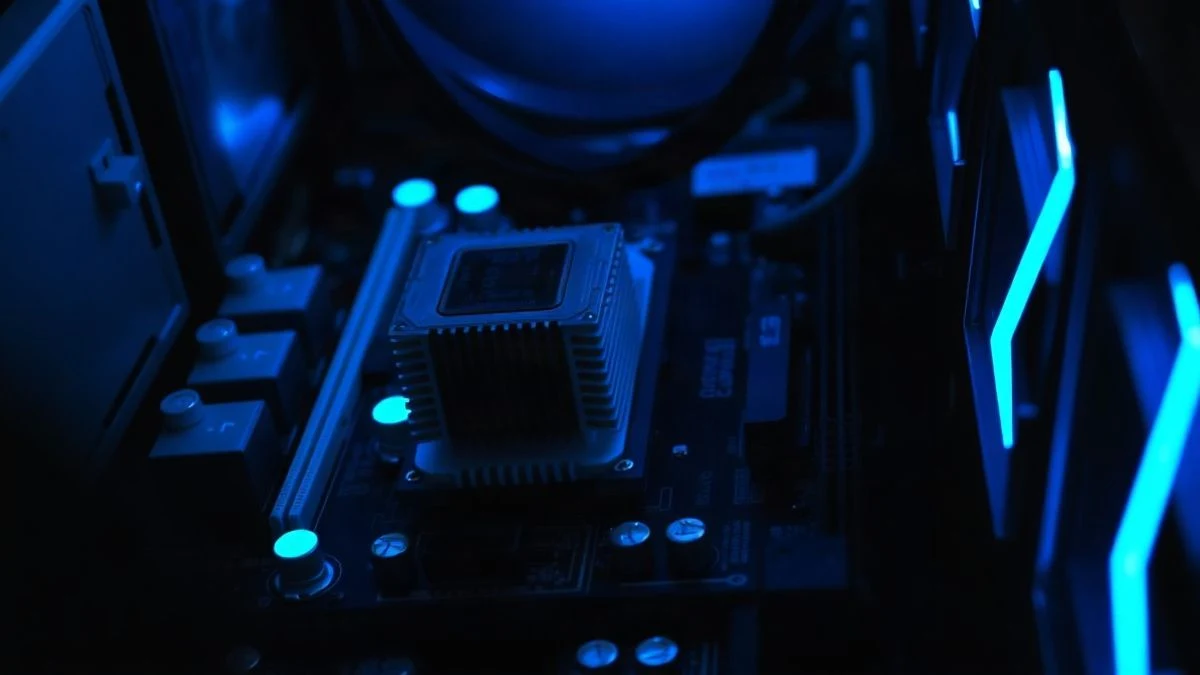 Imagen ilustrativa: primer plano de una placa base con zócalo de CPU y disipador, iluminada con luz azul tenue en un entorno oscuro.