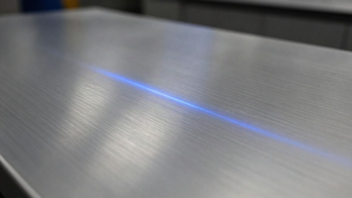Imagen ilustrativa: superficie de aluminio cepillado con reflejos azules de luz suave y fondo desenfocado